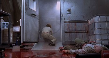 Movie still from “Hollow Man” (2000), directed by Paul Verhoeven – A woman in white shirt and brown pants in a room with blood on the floor; Wide shot, Low angle