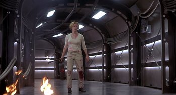 Movie still from “Hollow Man” (2000), directed by Paul Verhoeven – A woman with a knife in her hand and a fire in the background; Wide shot, Low angle