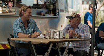 Movie still from “Holy Lands” (2017), directed by Amanda Sthers – Two men sitting at a table having a conversation; Medium shot, Over the shoulder angle