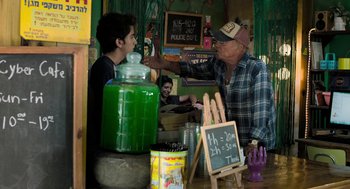 Movie still from “Holy Lands” (2017), directed by Amanda Sthers – A man in a plaid shirt is talking to a man in a plaid hat; Medium shot, Over the shoulder angle