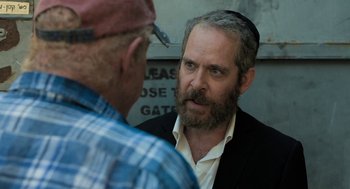 Movie still from “Holy Lands” (2017), directed by Amanda Sthers – A man with a beard talking to another man; Medium shot, Over the shoulder angle