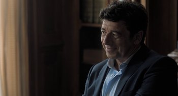 Movie still from “Holy Lands” (2017), directed by Amanda Sthers – A person wearing a suit and tie; Close Up shot, Over the shoulder angle