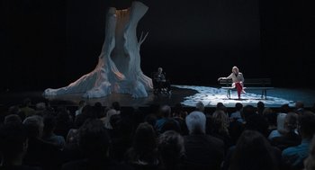 Movie still from “Holy Lands” (2017), directed by Amanda Sthers – Two people sitting on a stage in front of an audience; Extreme Wide shot, High angle