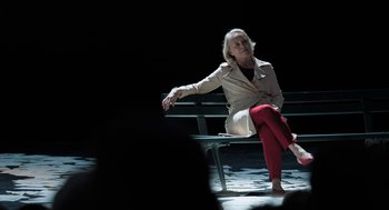 Movie still from “Holy Lands” (2017), directed by Amanda Sthers – A woman sitting on top of a wooden bench; Wide shot, High angle