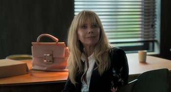 Movie still from “Holy Lands” (2017), directed by Amanda Sthers – A woman sitting at a table with a purse in front of a window; Close Up shot, Over the shoulder angle