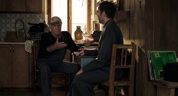 Movie still from “Holy Lands” (2017), directed by Amanda Sthers – Two men sitting at a table talking to each other; Medium shot, Over the shoulder angle