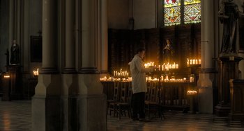 Movie still from “Holy Lands” (2017), directed by Amanda Sthers – A man standing in front of a bunch of lit candles; Extreme Wide shot, High angle