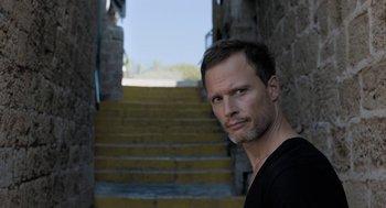 Movie still from “Holy Lands” (2017), directed by Amanda Sthers – A person standing in front of stairs; Close Up shot, Low angle
