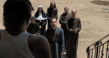 Movie still from “Holy Lands” (2017), directed by Amanda Sthers – A group of people dressed as monks standing in a field; Medium shot, High angle
