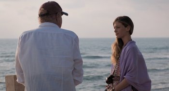 Movie still from “Holy Lands” (2017), directed by Amanda Sthers – A man and a woman standing next to each other on the beach; Medium shot, Over the shoulder angle