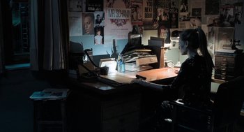 Movie still from “Holy Lands” (2017), directed by Amanda Sthers – A person sitting at a desk in a room; Wide shot, High angle