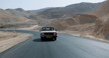 Movie still from “Holy Lands” (2017), directed by Amanda Sthers – A car driving down a road in the middle of the desert; Extreme Wide shot, High angle