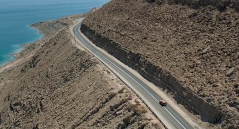 Movie still from “Holy Lands” (2017), directed by Amanda Sthers – An aerial view of a car driving down a road; Extreme Wide shot, High angle