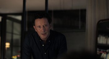Movie still from “Holy Lands” (2017), directed by Amanda Sthers – A man in a black shirt is sitting down; Close Up shot, Over the shoulder angle
