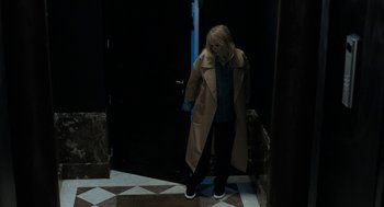 Movie still from “Holy Lands” (2017), directed by Amanda Sthers – A woman wearing a trench coat standing in front of a door; Wide shot, High angle