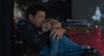 Movie still from “Holy Lands” (2017), directed by Amanda Sthers – A man and a woman hugging on a couch; Medium shot, High angle