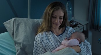 Movie still from “Holy Lands” (2017), directed by Amanda Sthers – A woman holding a baby in a hospital bed; Close Up shot, High angle