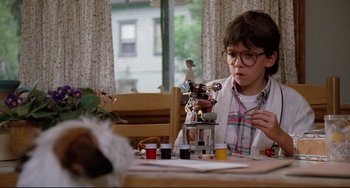 Movie still from “Honey, I Shrunk the Kids” (1989), directed by Joe Johnston – A young boy sitting at a dining room table; Medium shot, Low angle