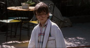 Movie still from “Honey, I Shrunk the Kids” (1989), directed by Joe Johnston – A young boy wearing glasses and a lab coat; Medium shot, Low angle