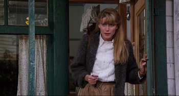 Movie still from “Honey, I Shrunk the Kids” (1989), directed by Joe Johnston – A woman standing in front of a door holding a cell phone; Medium shot, Over the shoulder angle