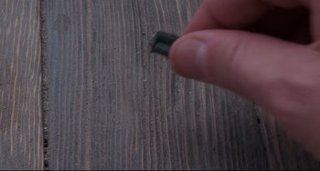Movie still from “Honey, I Shrunk the Kids” (1989), directed by Joe Johnston – A hand holding a piece of wood on top of a wooden table; Extreme Close Up shot, Overhead angle