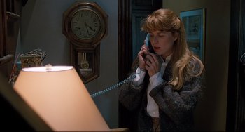 Movie still from “Honey, I Shrunk the Kids” (1989), directed by Joe Johnston – A woman talking on a phone while standing in front of a clock; Medium shot, High angle