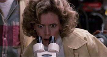 Movie still from “Honey, I Shrunk the Kids” (1989), directed by Joe Johnston – A woman looking into a microscope with a surprised look on her face; Close Up shot, High angle