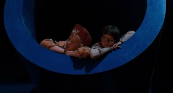 Movie still from “Honey, I Shrunk the Kids” (1989), directed by Joe Johnston – A couple of people that are laying down on a bench; Wide shot, Overhead angle