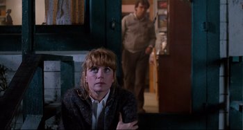 Movie still from “Honey, I Shrunk the Kids” (1989), directed by Joe Johnston – A woman sitting in front of a man in front of a door; Medium shot, Over the shoulder angle