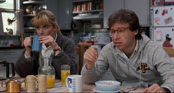 Movie still from “Honey, I Shrunk the Kids” (1989), directed by Joe Johnston – A man and a woman sitting at a table eating cereal; Medium shot, Over the shoulder angle