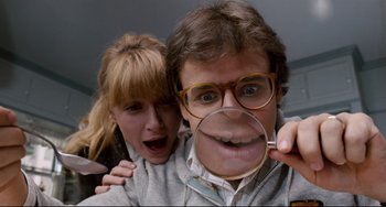 Movie still from “Honey, I Shrunk the Kids” (1989), directed by Joe Johnston – A man and a woman holding a magnifying glass up to their faces; Extreme Close Up shot, Low angle