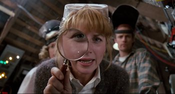 Movie still from “Honey, I Shrunk the Kids” (1989), directed by Joe Johnston – A woman holding a magnifying glass over her head; Close Up shot, Over the shoulder angle