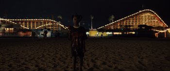 Movie still from “Us” (2019), directed by Jordan Peele – A little boy standing on the beach at night; Wide shot, High angle