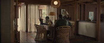 Movie still from “Us” (2019), directed by Jordan Peele – A group of people sitting at a table in front of a window; Wide shot, High angle