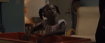 Movie still from “Us” (2019), directed by Jordan Peele – A little girl sitting on top of a table looking up; Close Up shot, High angle