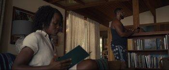 Movie still from “Us” (2019), directed by Jordan Peele – Two people sitting in a living room reading a book; Medium shot, Over the shoulder angle