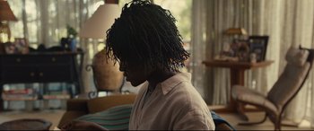 Movie still from “Us” (2019), directed by Jordan Peele – A man with a dread lock sitting in front of a window; Medium shot, Over the shoulder angle