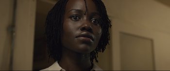 Movie still from “Us” (2019), directed by Jordan Peele – A person wearing a white shirt; Close Up shot, Low angle