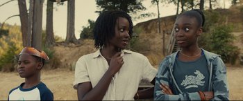 Movie still from “Us” (2019), directed by Jordan Peele – A young woman with dreadlocks standing next to a man; Close Up shot, Over the shoulder angle