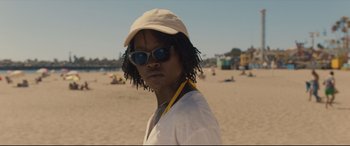 Movie still from “Us” (2019), directed by Jordan Peele – A man with dreadlocks wearing sunglasses and a hat; Close Up shot, Over the shoulder angle