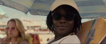 Movie still from “Us” (2019), directed by Jordan Peele – A person wearing a hat and sunglasses; Close Up shot, Over the shoulder angle