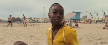 Movie still from “Us” (2019), directed by Jordan Peele – A young woman wearing a yellow jacket and ear buds; Close Up shot, High angle