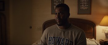Movie still from “Us” (2019), directed by Jordan Peele – A man in a gray shirt is sitting in front of a bed; Medium shot, Over the shoulder angle