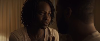 Movie still from “Us” (2019), directed by Jordan Peele – A young woman talking to a man in a dark room; Close Up shot, Over the shoulder angle