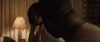 Movie still from “Us” (2019), directed by Jordan Peele – A young woman looking in the mirror in front of a mirror; Close Up shot, Over the shoulder angle