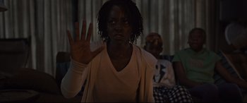 Movie still from “Us” (2019), directed by Jordan Peele – A woman is holding her hand up in front of her face; Medium shot, Over the shoulder angle