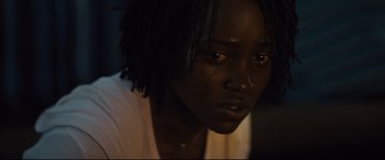 Movie still from “Us” (2019), directed by Jordan Peele – A person with a crying face; Close Up shot, Over the shoulder angle