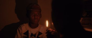 Movie still from “Us” (2019), directed by Jordan Peele – A young man holding a lit candle in front of a mirror; Close Up shot, Over the shoulder angle