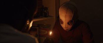 Movie still from “Us” (2019), directed by Jordan Peele – A person is holding a lit candle in a room; Close Up shot, Low angle