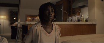 Movie still from “Us” (2019), directed by Jordan Peele – A woman with a dreadlocks stands in a kitchen; Close Up shot, Over the shoulder angle